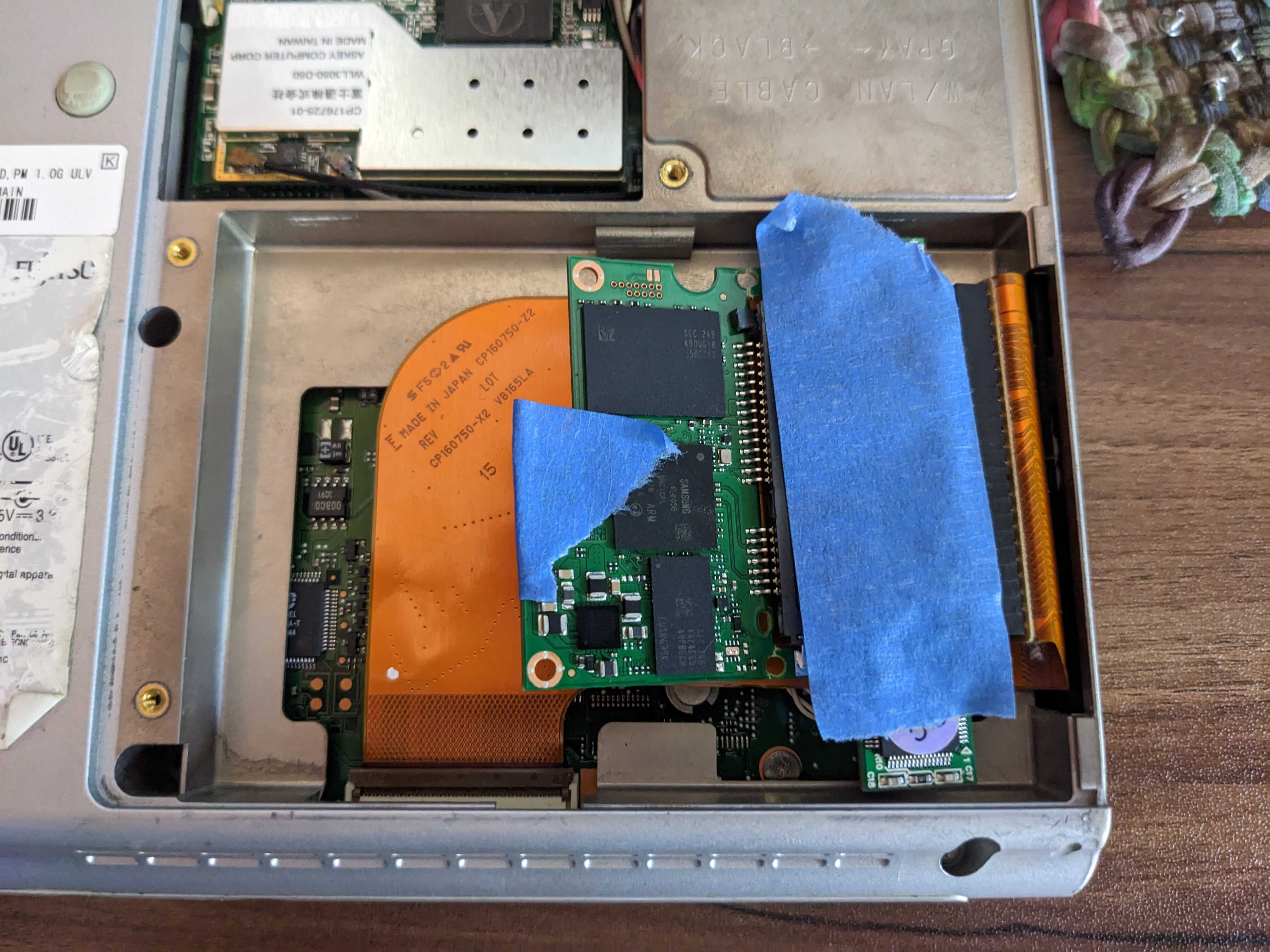 SSD inside of laptop's drive bay with tape.